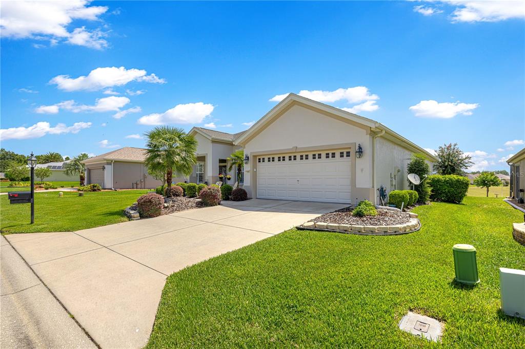 A single-story suburban house with a two-car garage, concrete driveway, and landscaped front yard — 11855 SE 91ST CIRCLE, SUMMERFIELD, FL
