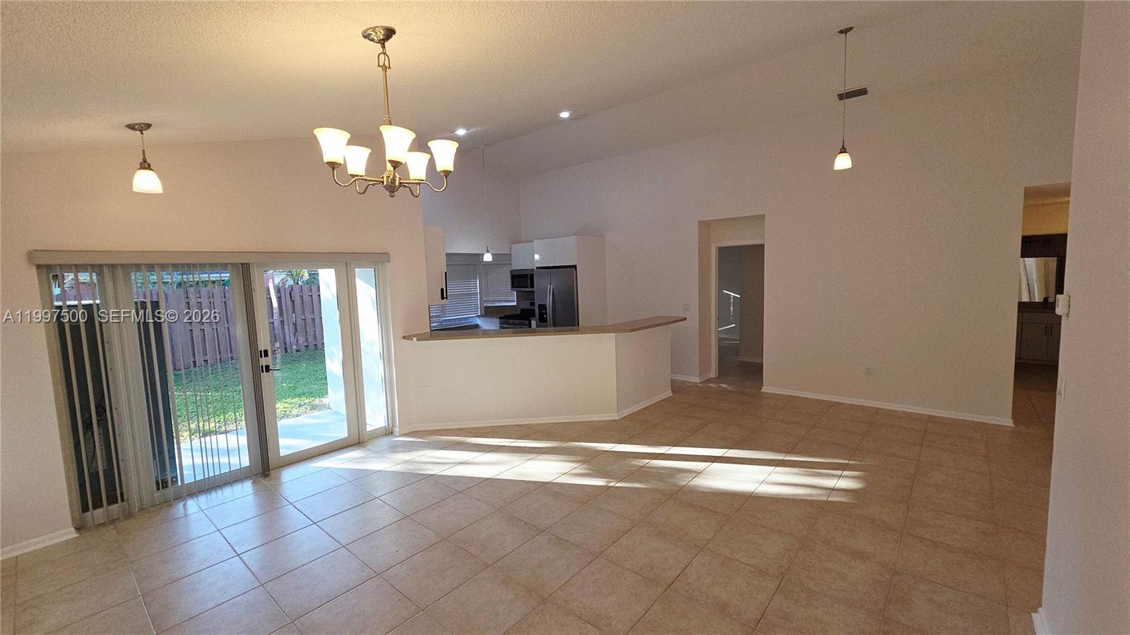 An open-concept living area features tile flooring, a kitchen breakfast bar, and sliding glass doors — 3247 NW 123rd Ave, Sunrise FL 33323, SUNRISE, FL