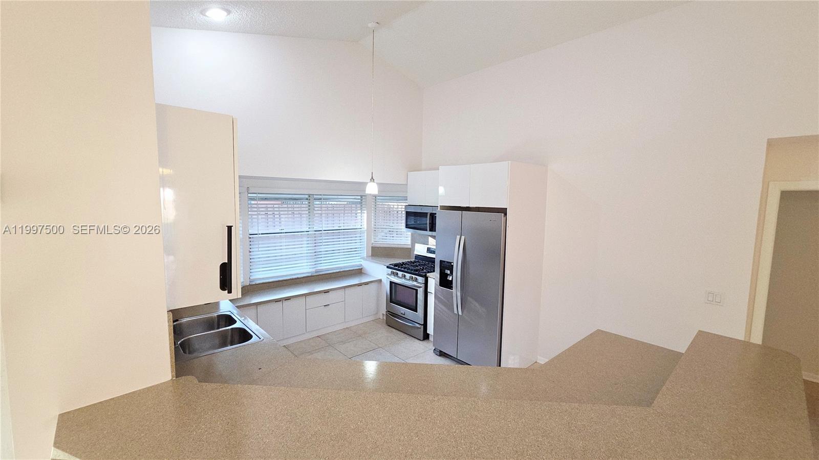 A kitchen features white cabinetry, stainless steel appliances, and a breakfast bar with countertops — 3247 NW 123rd Ave, Sunrise FL 33323, SUNRISE, FL