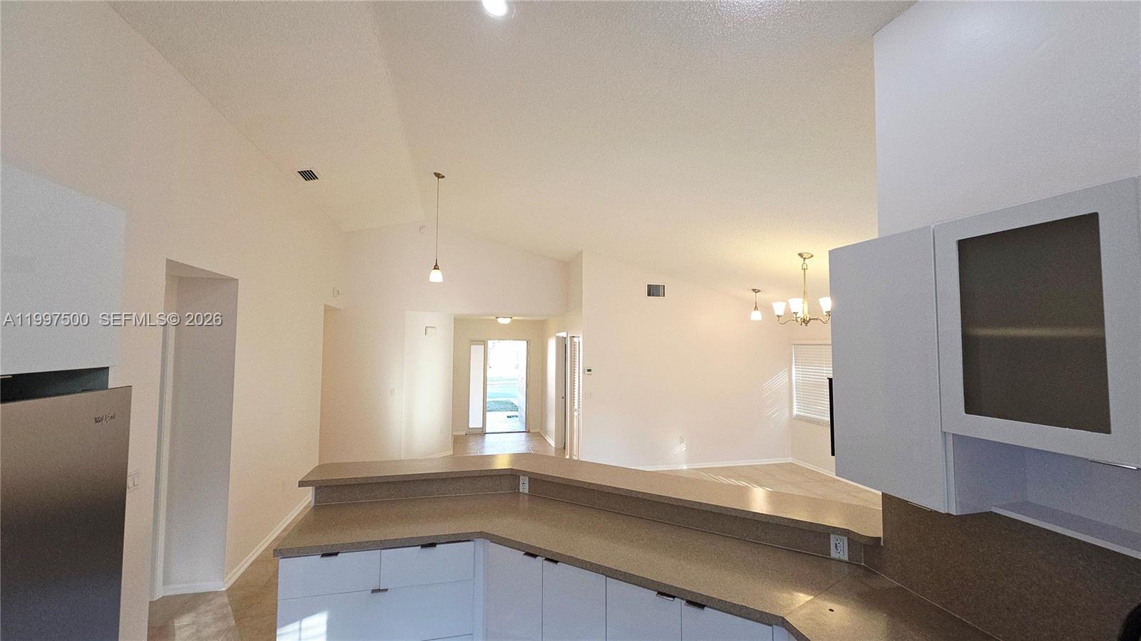 A kitchen counter overlooks an open living area with vaulted ceilings and a front entrance — 3247 NW 123rd Ave, Sunrise FL 33323, SUNRISE, FL