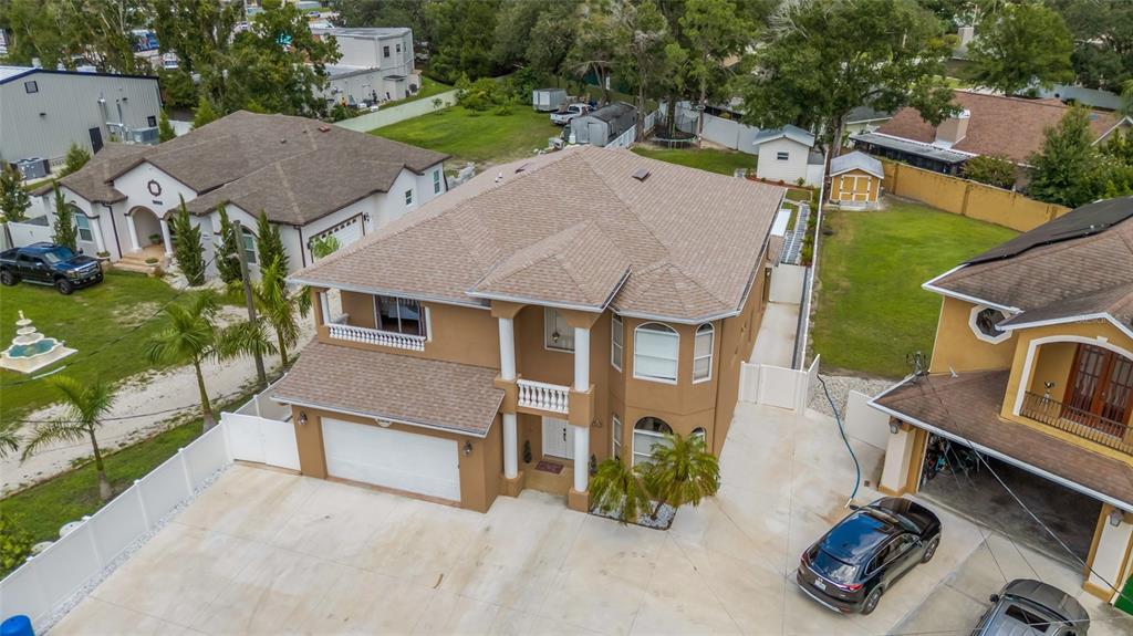 An aerial view shows a two-story tan house with a garage and a concrete driveway — 10806 PEREZ DRIVE, TAMPA, FL
