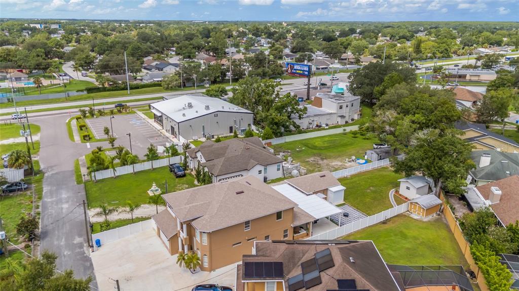 An aerial view shows a tan multi-story house with a white fence and surrounding properties — 10806 PEREZ DRIVE, TAMPA, FL