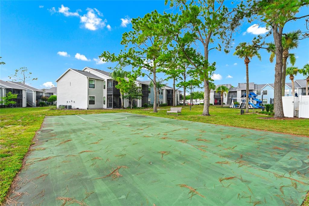A green outdoor basketball court sits in front of apartment buildings with trees and grass — 3740 IDLEBROOK CIRCLE UNIT 102, CASSELBERRY, FL