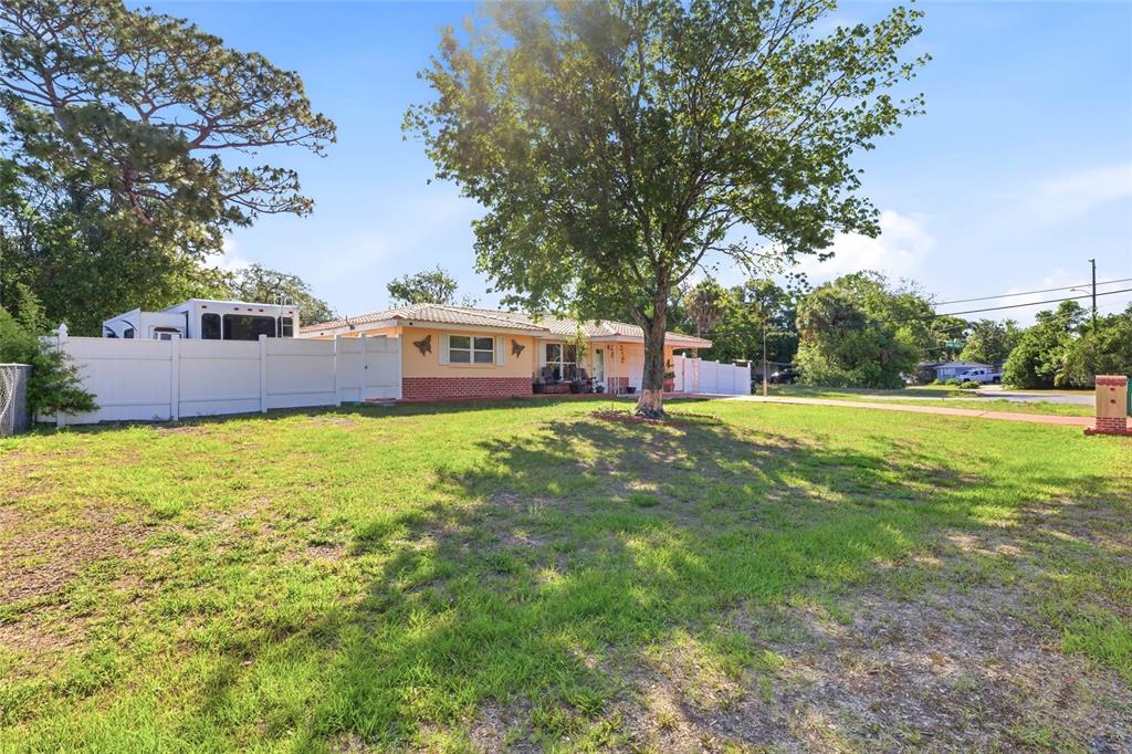 A single-story house with a white fence and a large tree in the front yard — 6760 RUNNEL DRIVE, NEW PORT RICHEY, FL