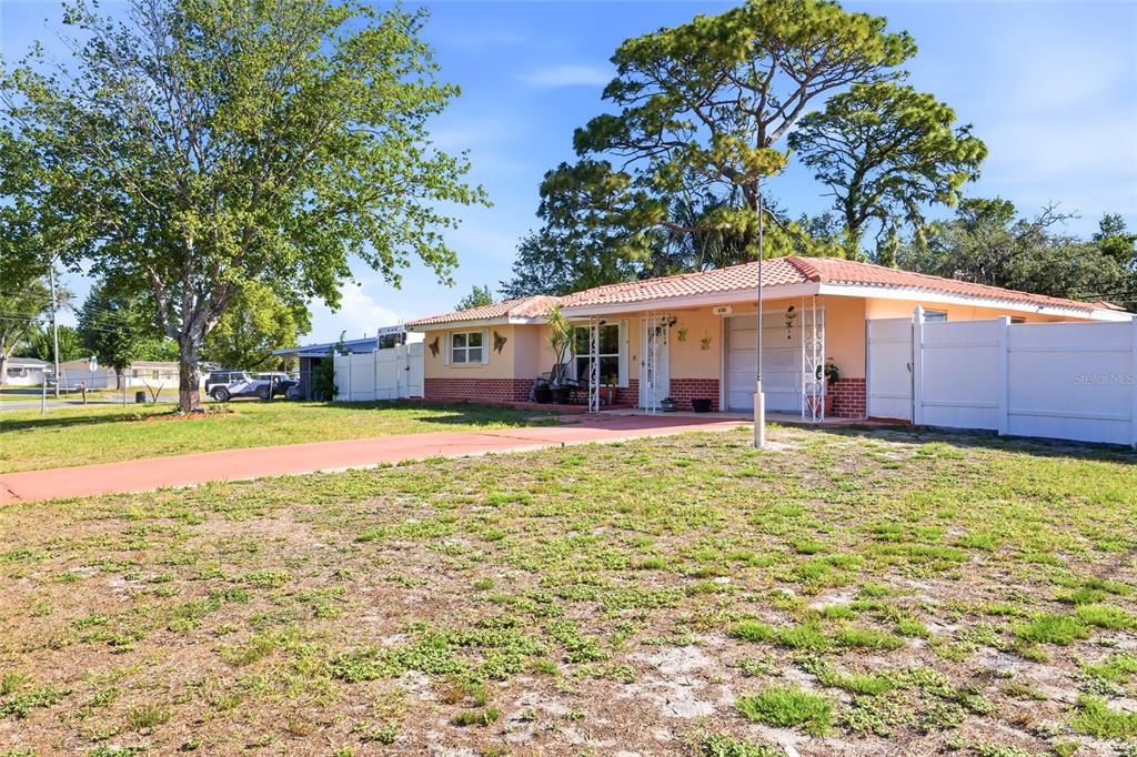 A single-story house with a peach exterior, red tile roof, and a white vinyl fence — 6760 RUNNEL DRIVE, NEW PORT RICHEY, FL