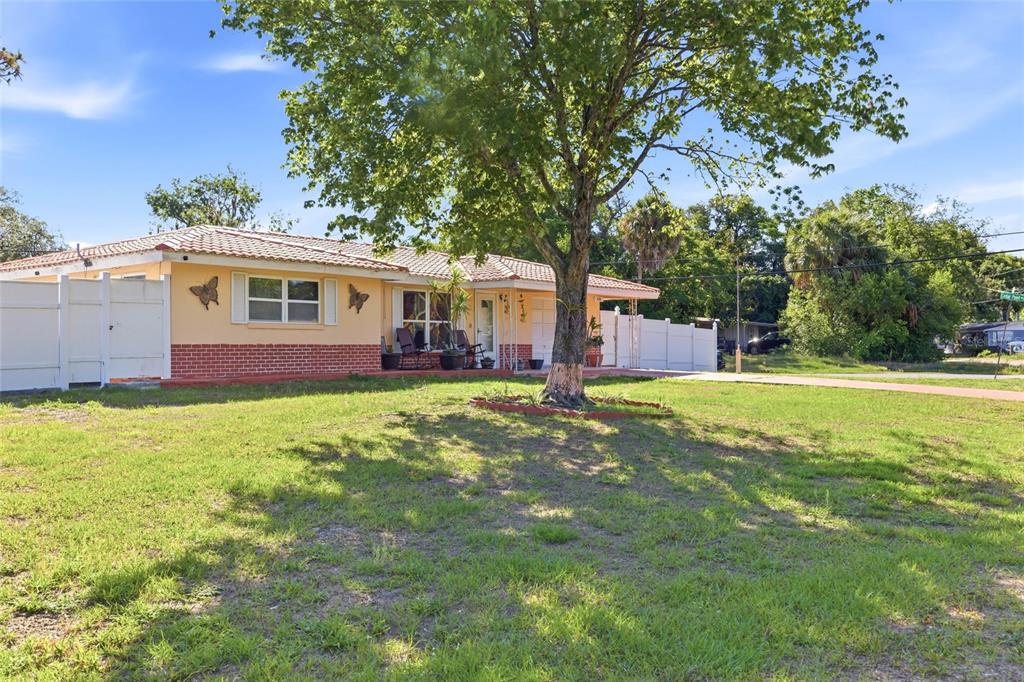 A single-story house with a light-colored exterior, brick accents, and a large tree in front — 6760 RUNNEL DRIVE, NEW PORT RICHEY, FL
