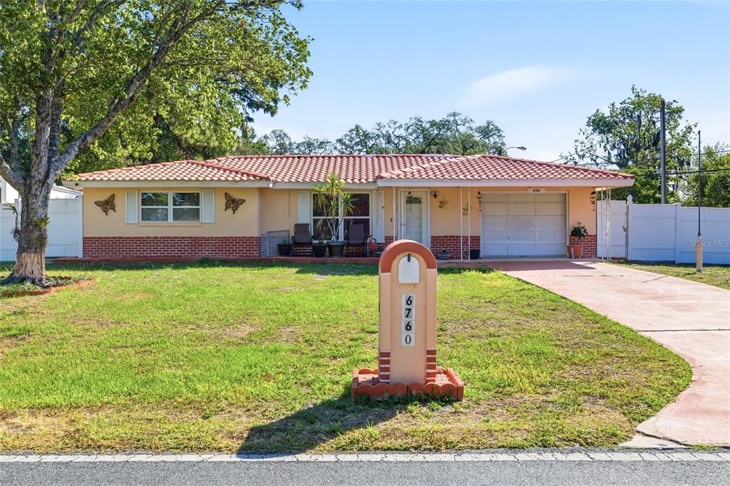 A single-story house with a red tile roof, peach exterior, and a front lawn — 6760 RUNNEL DRIVE, NEW PORT RICHEY, FL