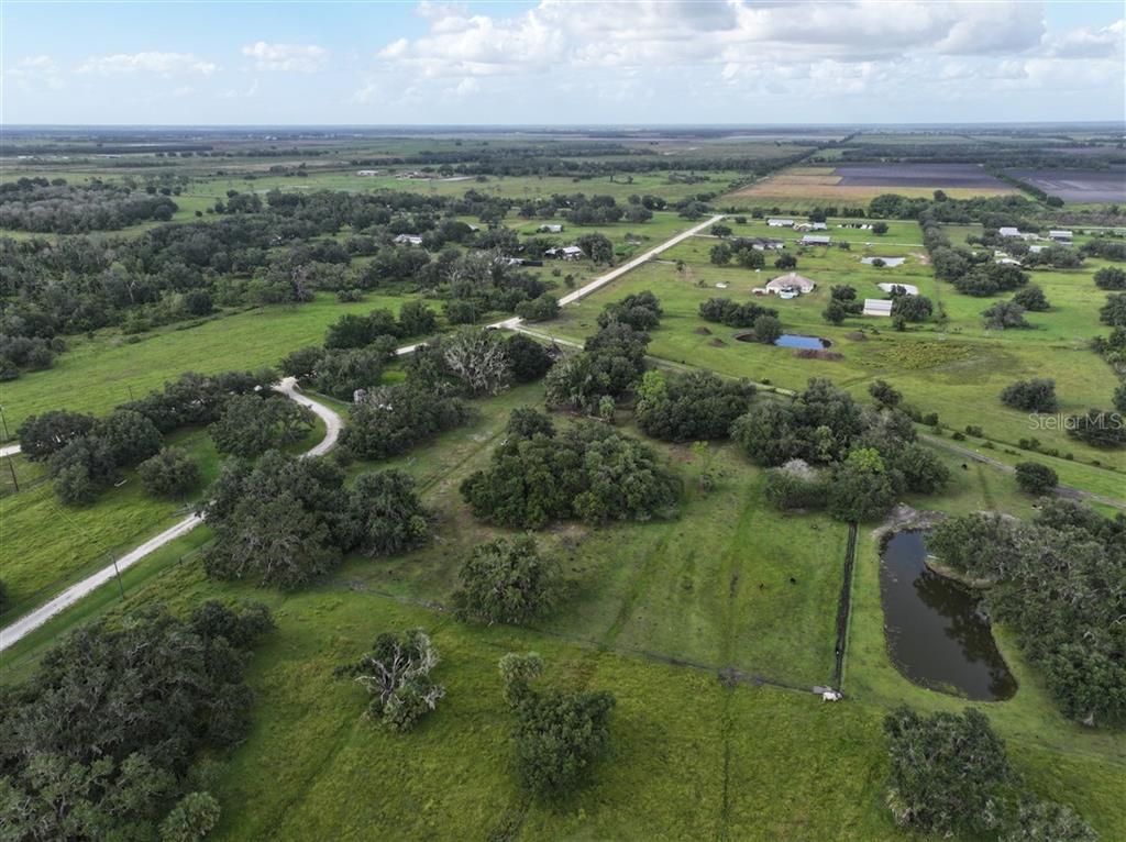 An aerial view shows a large, grassy rural property with scattered trees and a pond — 14935 COKER GULLY ROAD, MYAKKA CITY, FL