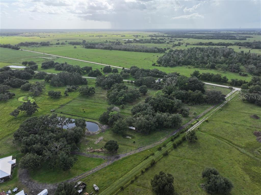 An aerial view shows a large, grassy rural property with scattered trees and a pond — 14935 COKER GULLY ROAD, MYAKKA CITY, FL