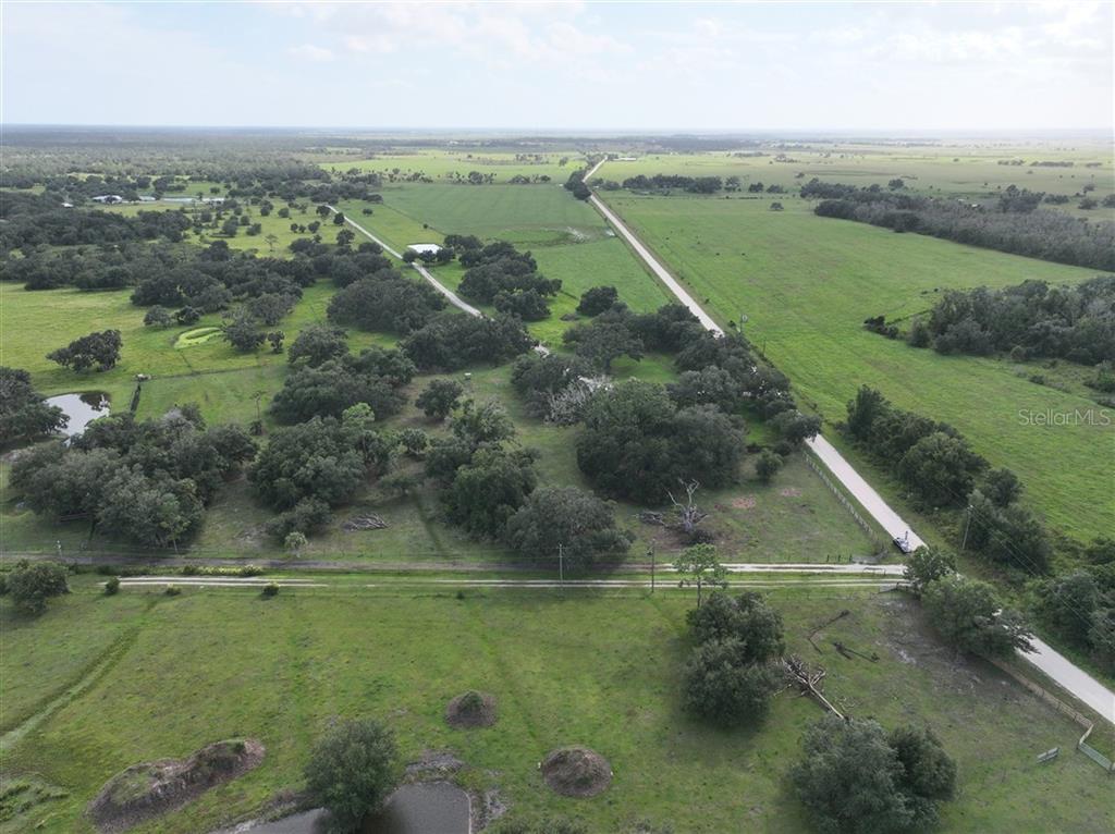 An aerial view shows a large, grassy rural property with scattered trees and dirt roads — 14935 COKER GULLY ROAD, MYAKKA CITY, FL