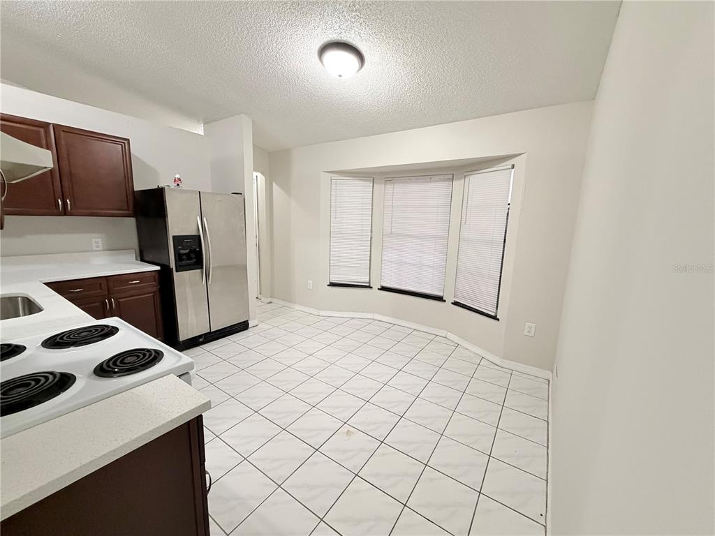 A kitchen with dark wood cabinets, stainless steel appliances, and white tile flooring — 2873 COTTONDALE DRIVE, DELTONA, FL