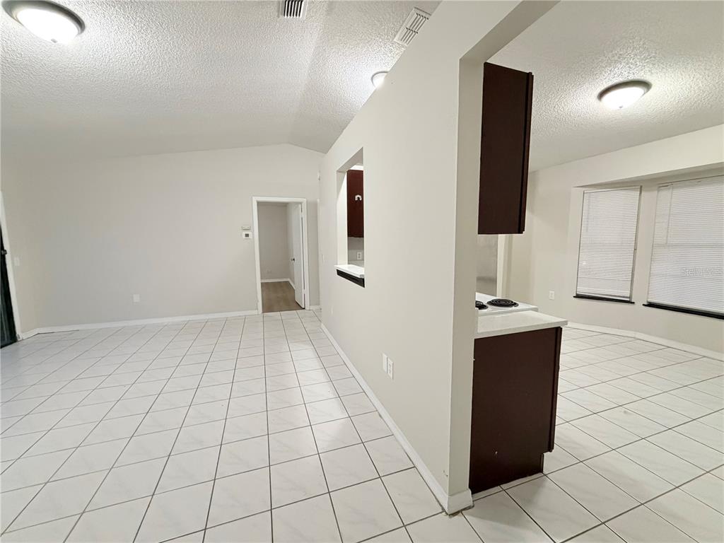 A tiled living area features a pass-through window looking into a kitchen with dark cabinets — 2873 COTTONDALE DRIVE, DELTONA, FL