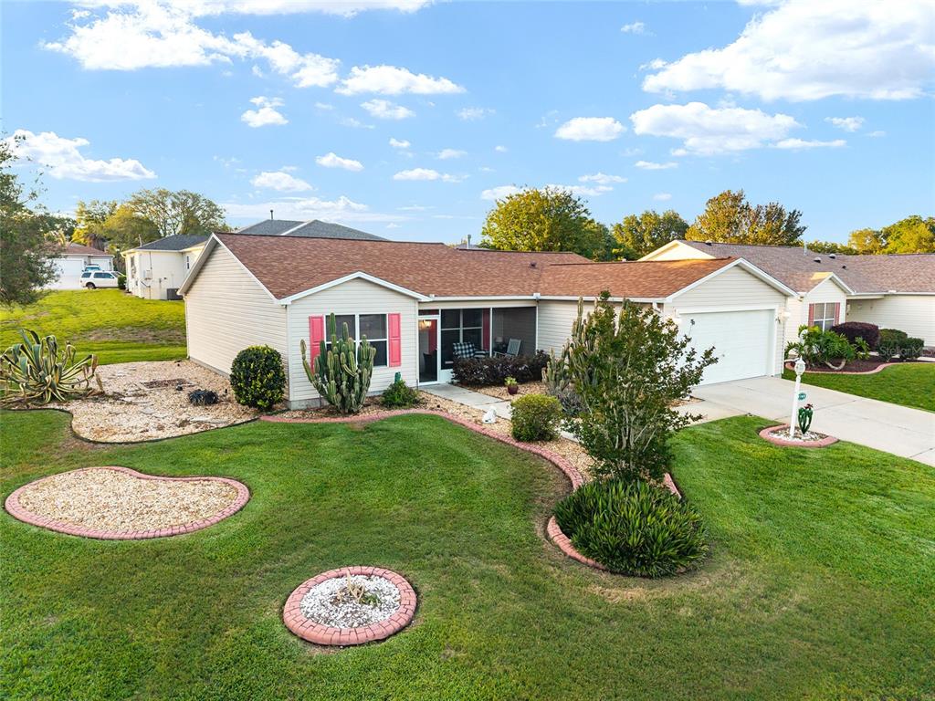 A single-story house with a tan exterior, brown roof, and a landscaped front yard — 17009 SE 96TH CHAPELWOOD CIRCLE, THE VILLAGES, FL