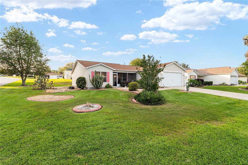 A single-story house with light siding, a two-car garage, and a landscaped front lawn — 17009 SE 96TH CHAPELWOOD CIRCLE, THE VILLAGES, FL