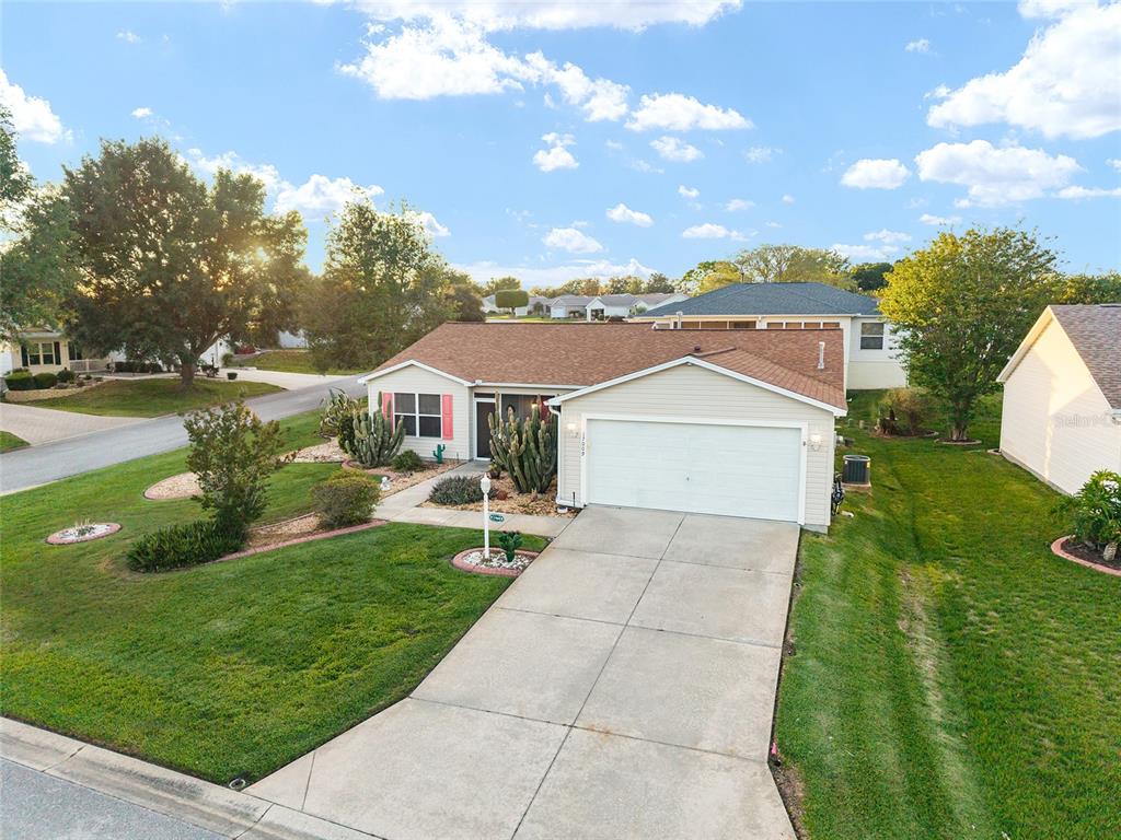 An exterior view of a single-story house with a tan facade, brown roof, and driveway — 17009 SE 96TH CHAPELWOOD CIRCLE, THE VILLAGES, FL