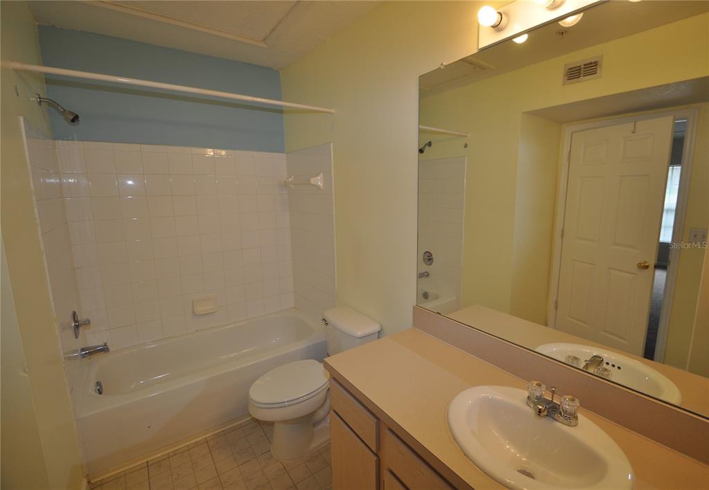 A bathroom features a white bathtub, a toilet, and a vanity with a sink — 738 CREST PINES DRIVE UNIT 734, ORLANDO, FL