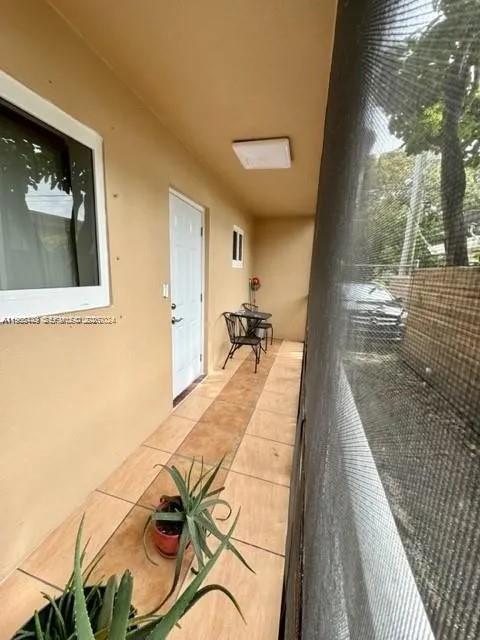A covered outdoor patio features tiled flooring, a white door, and a screened-in wall — 1840 Dewey St # 103, Hollywood FL 33020, HOLLYWOOD, FL