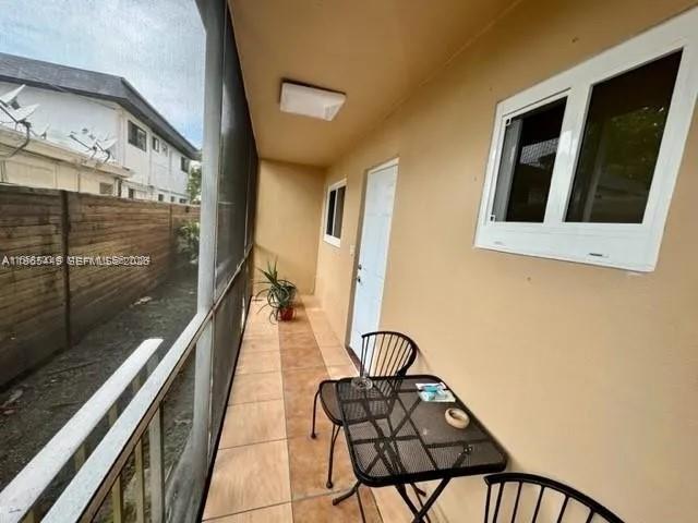 A screened-in patio features a small metal table, two chairs, and a potted plant — 1840 Dewey St # 103, Hollywood FL 33020, HOLLYWOOD, FL