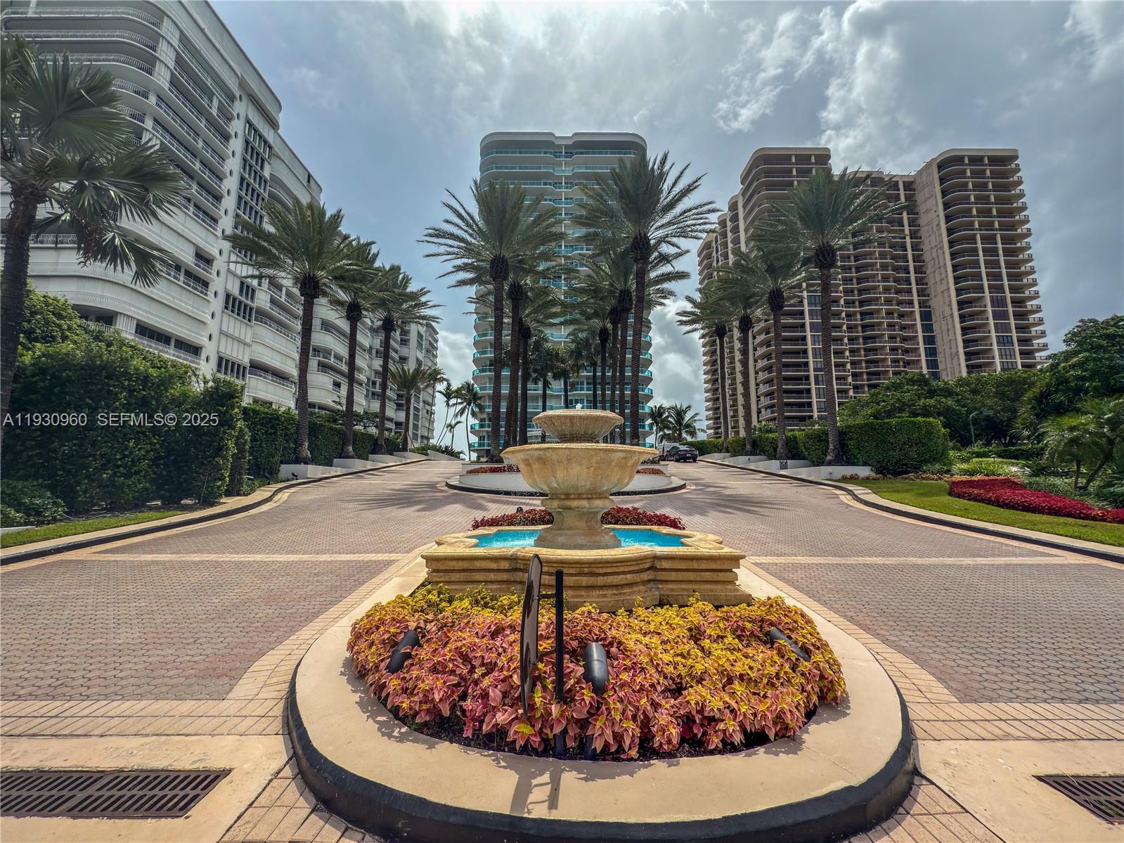 A stone fountain sits in the center of a paved driveway between three tall buildings — 10101 Collins Ave # 4A, Bal Harbour FL 33154, BAL HARBOUR, FL