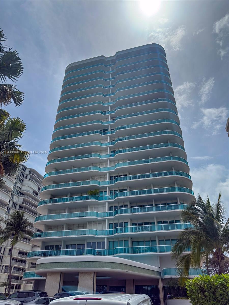 A tall residential high-rise building features curved balconies with glass railings against a blue sky — 10101 Collins Ave # 4A, Bal Harbour FL 33154, BAL HARBOUR, FL