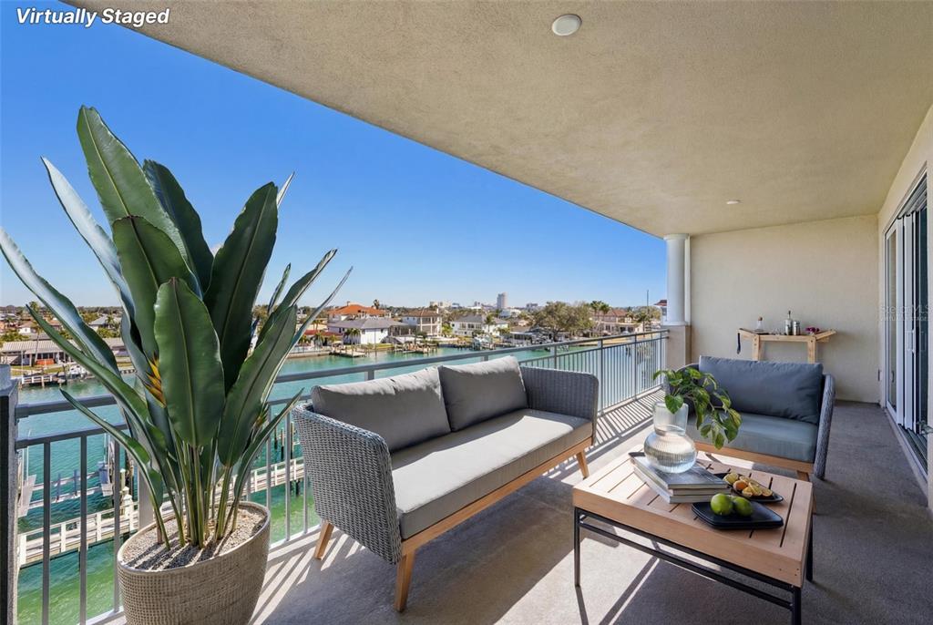 A balcony with outdoor furniture overlooks a canal and residential neighborhood on a sunny day — 125 ISLAND WAY UNIT 404, CLEARWATER BEACH, FL