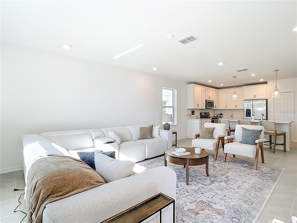 A living room with a white sectional sofa, two armchairs, and an open kitchen — 16863 FIESTA DRIVE, PORT CHARLOTTE, FL