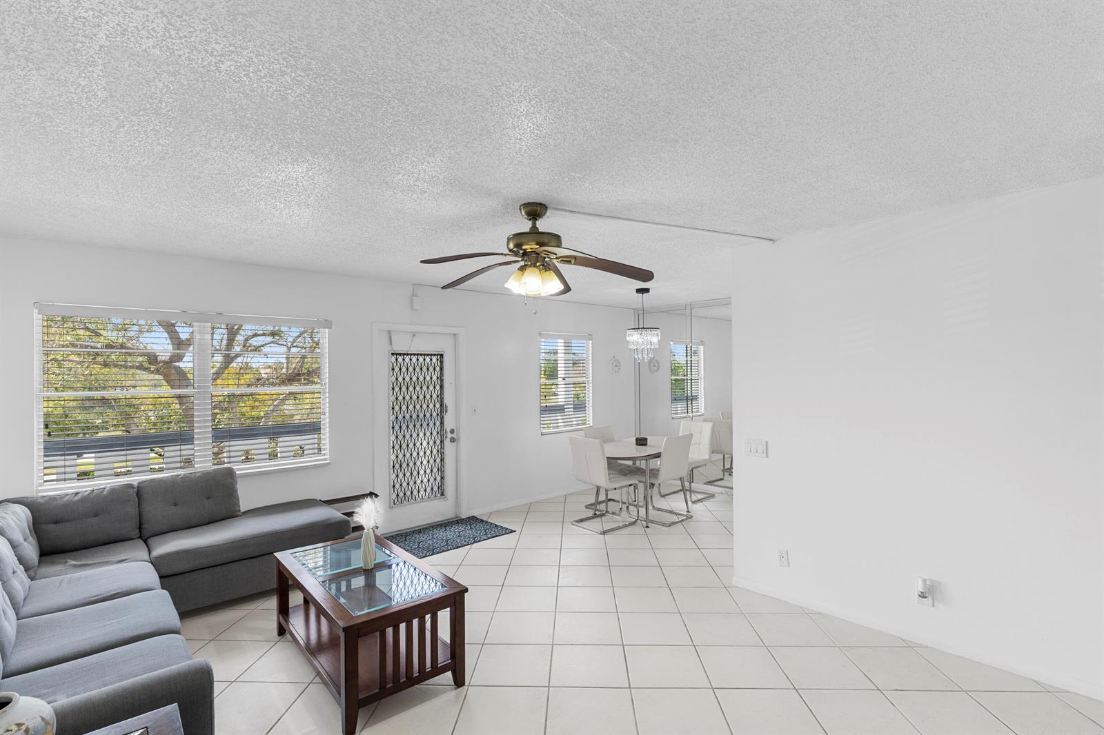 A living and dining area features white tile floors, a ceiling fan, and a sofa — 3028 Harwood D, Deerfield Beach FL 33442, DEERFIELD BEACH, FL