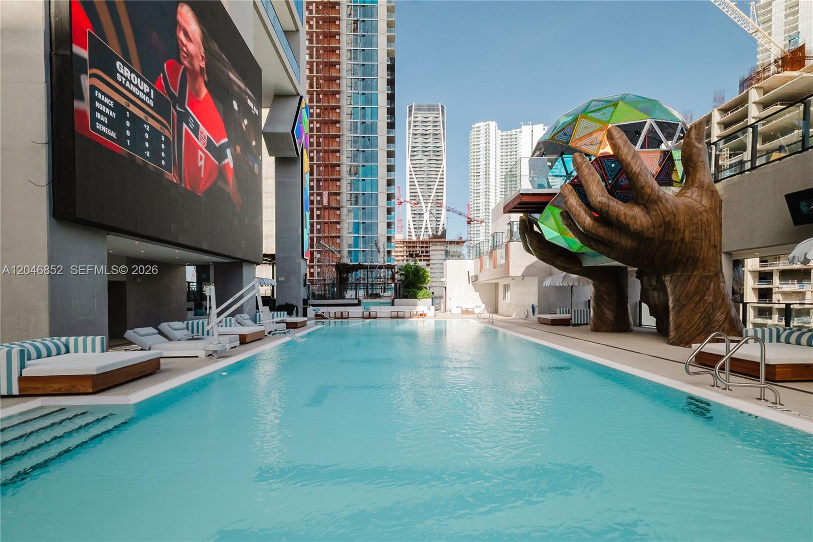 An outdoor swimming pool features a large sculpture of hands holding a geometric sphere — 20 NE 11th st # 4907A, Miami FL 33132, MIAMI, FL