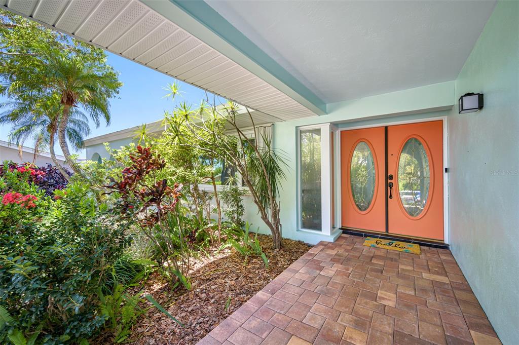A covered entryway features a paver floor, light green walls, and bright orange double doors — 3749 MCKAY CREEK DRIVE, LARGO, FL