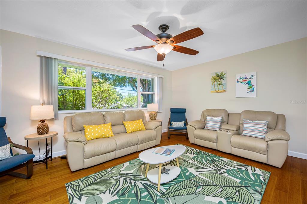 A living room features two beige sofas, a tropical-patterned rug, and a ceiling fan — 3749 MCKAY CREEK DRIVE, LARGO, FL