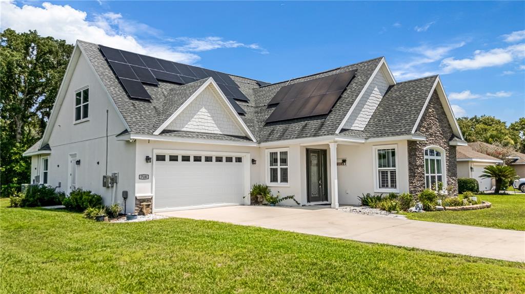 A single-story house with a white exterior, stone accents, and solar panels on the roof — 728 LAKE DIAMOND AVENUE, OCALA, FL