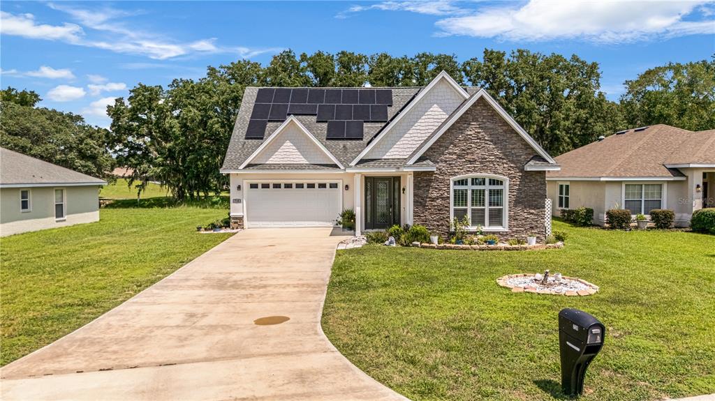 A single-story house with a stone facade, solar panels on the roof, and a driveway — 728 LAKE DIAMOND AVENUE, OCALA, FL