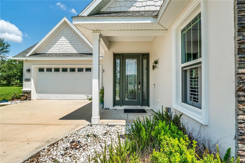 The exterior of a house features a white stucco facade, a garage, and a front door — 728 LAKE DIAMOND AVENUE, OCALA, FL