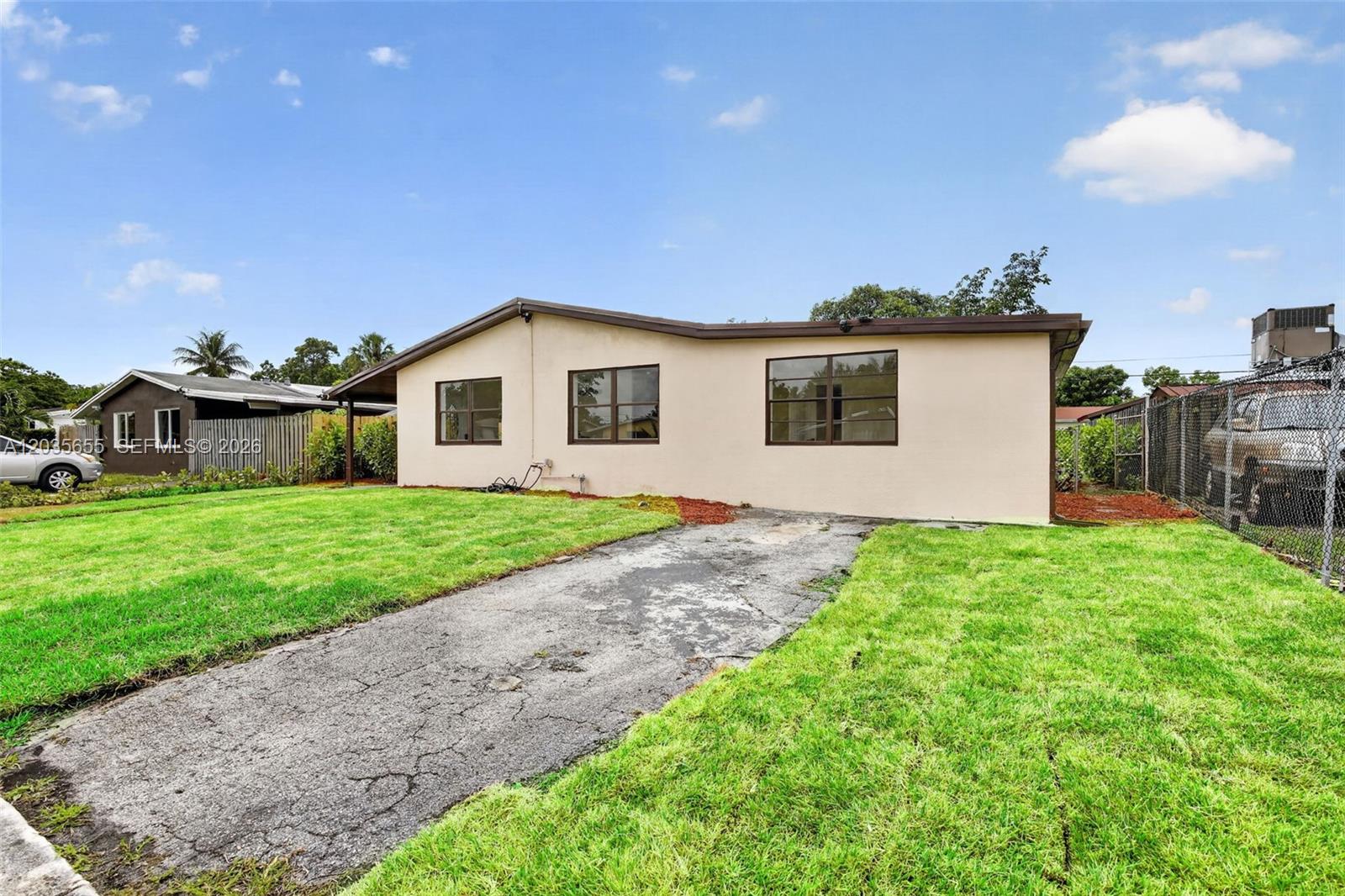 A single-story house with a beige exterior, a concrete driveway, and a grassy front yard — 6250 NW 14th St, Sunrise FL 33313, SUNRISE, FL