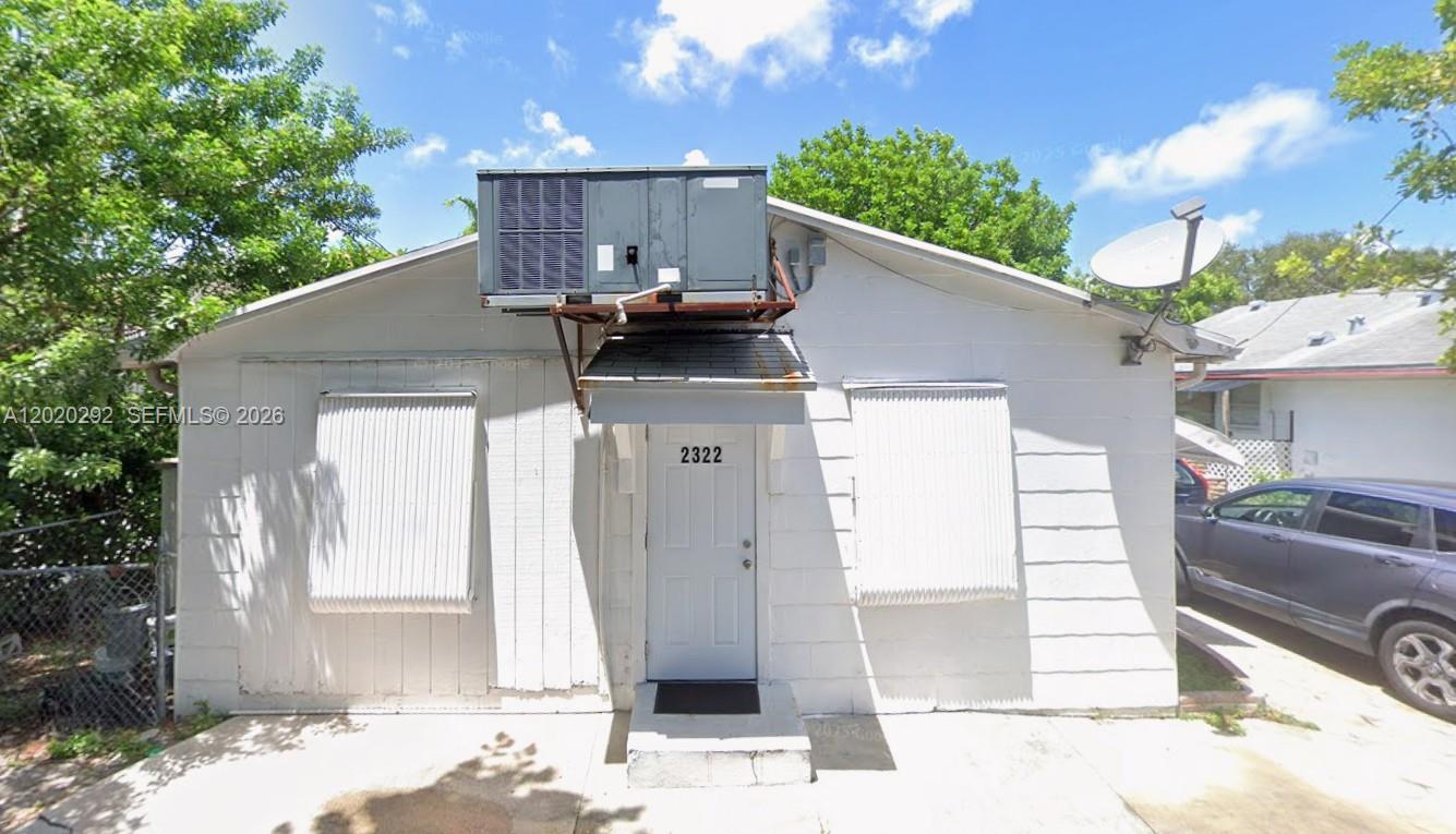 The exterior of a white, single-story house features a prominent roof-mounted air conditioning unit — 2322 Taft St, Hollywood FL 33020, HOLLYWOOD, FL