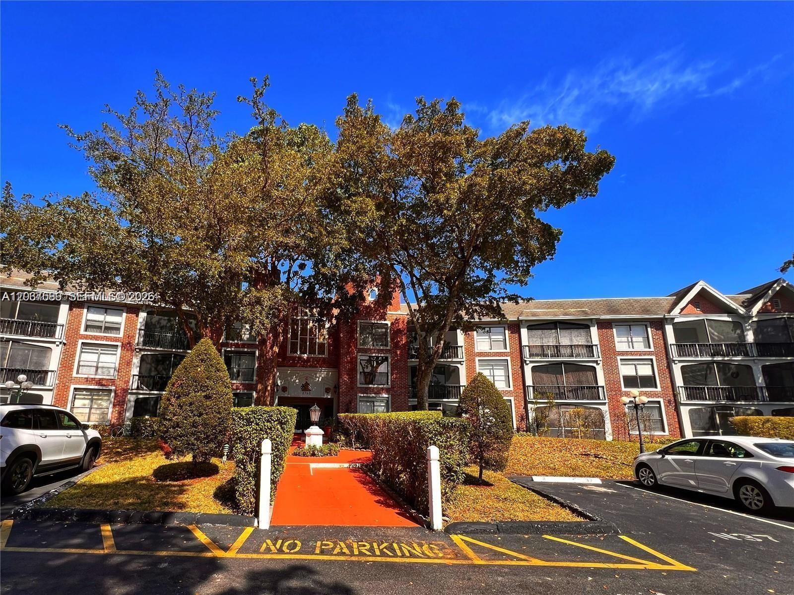 A three-story brick apartment building features balconies and a central red walkway entrance — 3760 Inverrary Dr # 2R, Lauderhill FL 33319, LAUDERHILL, FL