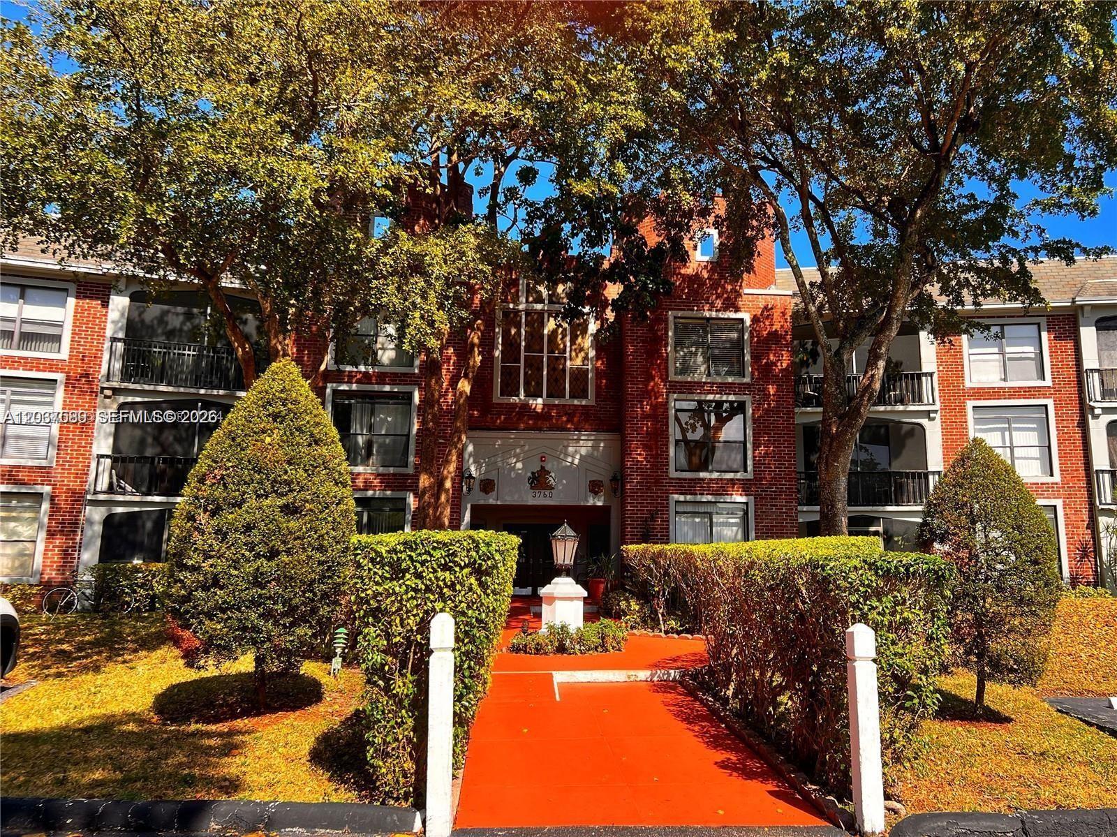 A red brick apartment building features a central entrance path and mature trees — 3760 Inverrary Dr # 2R, Lauderhill FL 33319, LAUDERHILL, FL
