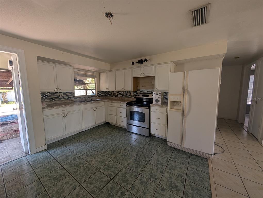A kitchen with white cabinets, stainless steel appliances, tiled floors, and a tiled backsplash — 2731 17TH STREET, SARASOTA, FL