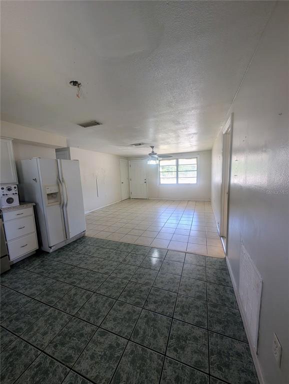 A kitchen with tile flooring and a white refrigerator opens into a living area — 2731 17TH STREET, SARASOTA, FL