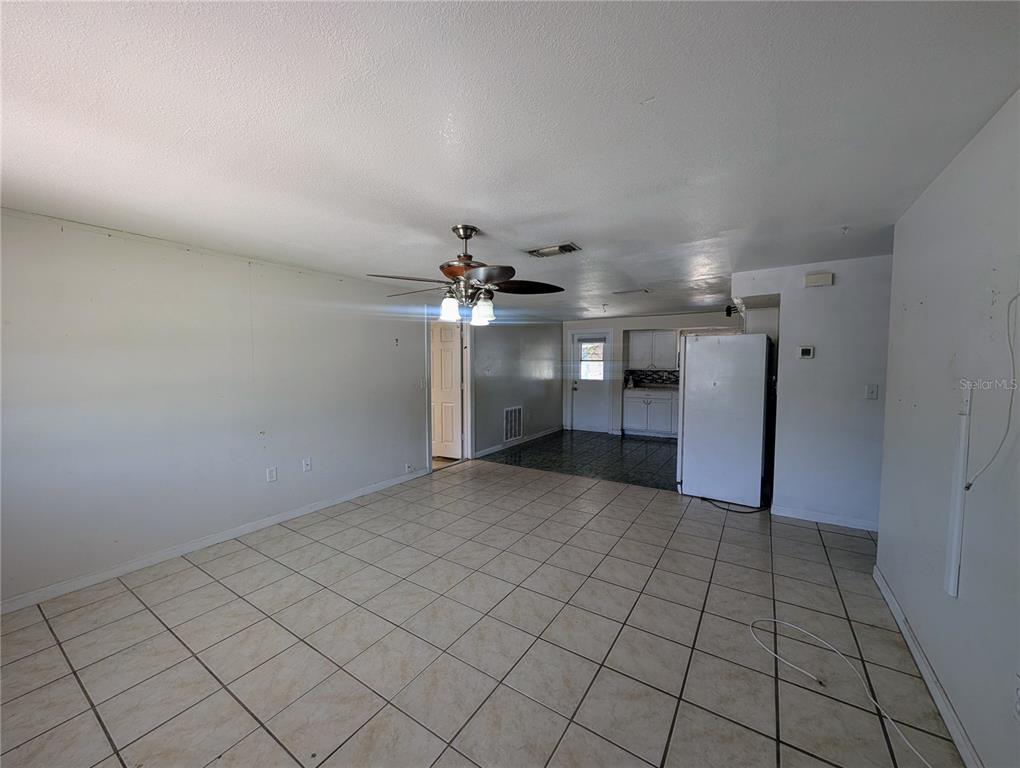 An open-concept room features light-colored tile flooring, a ceiling fan, and a white refrigerator — 2731 17TH STREET, SARASOTA, FL