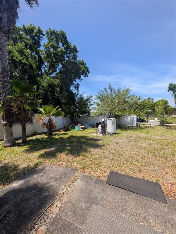 A grassy backyard features a concrete patio, palm trees, and a white vinyl fence — 2731 17TH STREET, SARASOTA, FL