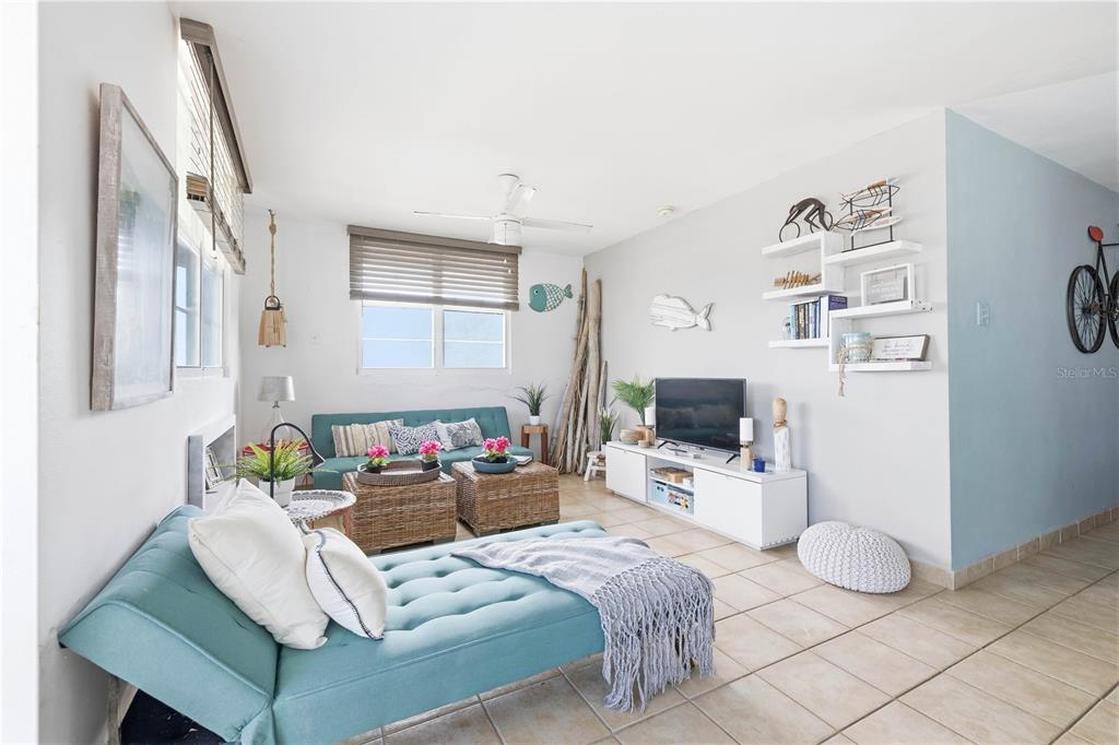 A living room features a teal chaise lounge, a matching sofa, and a white media console — Haudimar Beach Apartments 4466 UNIT F208, ISABELA, PR