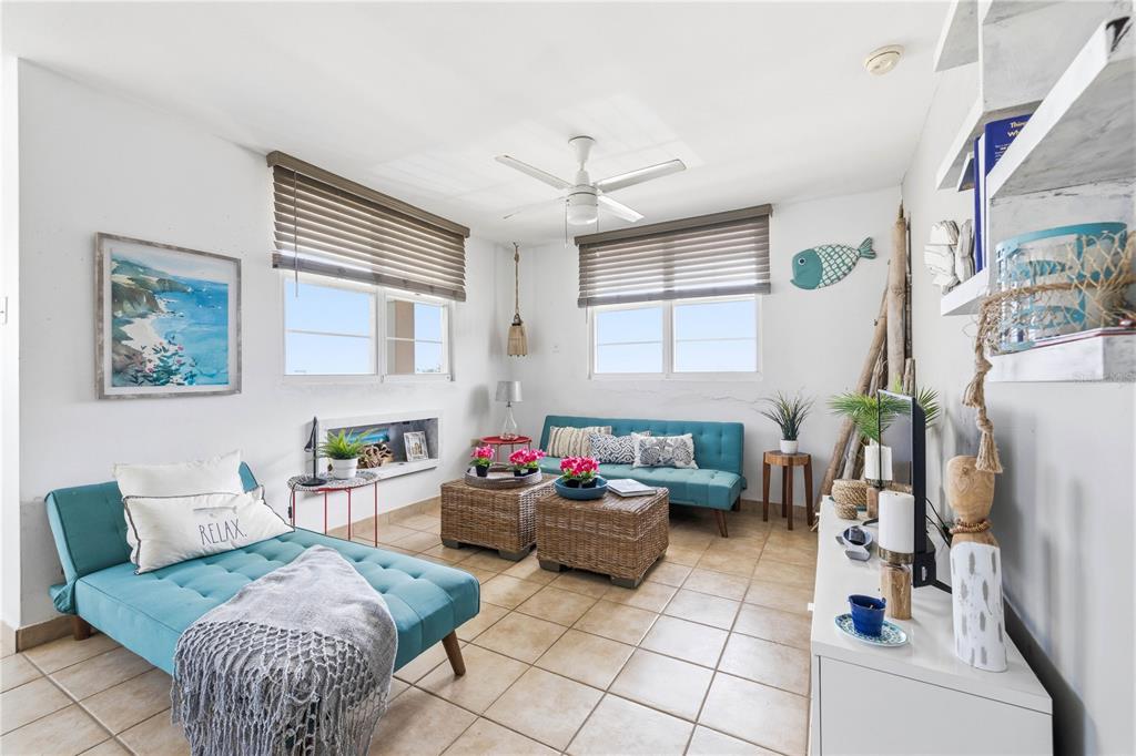 A living room features two teal sofas, wicker coffee tables, and tile flooring — Haudimar Beach Apartments 4466 UNIT F208, ISABELA, PR