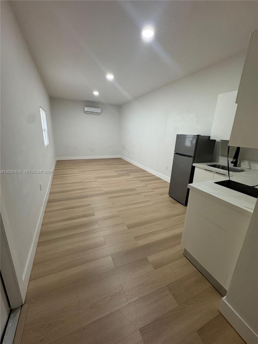 This room features light wood-look flooring, white walls, recessed lighting, and a small kitchenette — MIAMI, FL