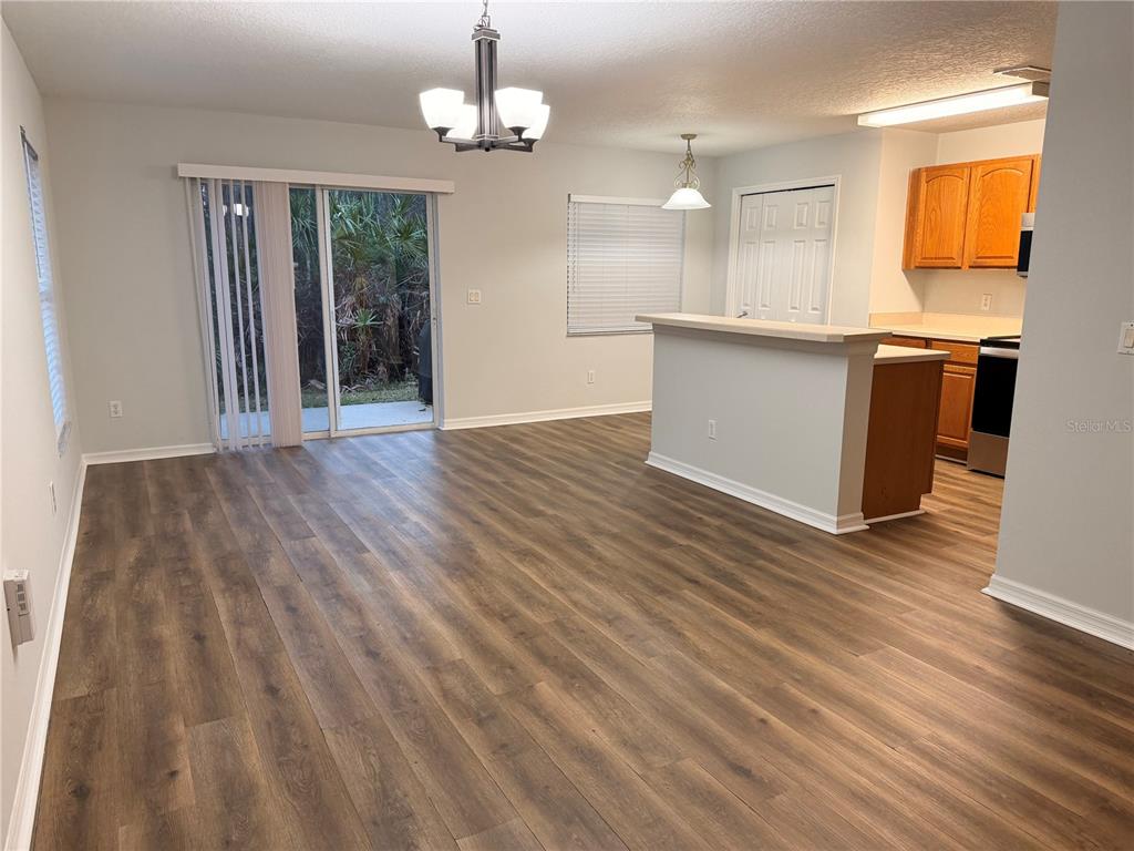 An open-concept dining and kitchen area features wood-look flooring, a breakfast bar, and sliding doors — 3623 CARUSO PLACE, OVIEDO, FL
