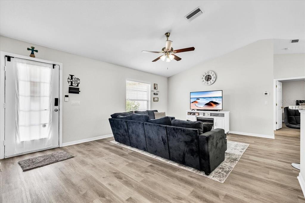 A living room features a dark sectional sofa, a television on a white stand, and light-colored flooring — 3776 JUNCTION STREET, NORTH PORT, FL