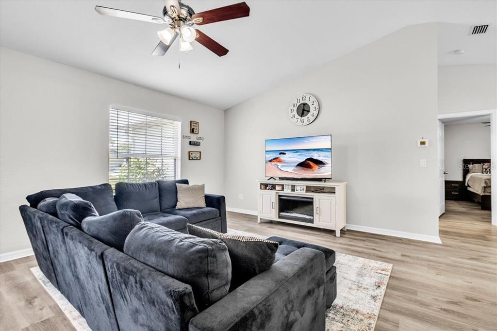 A living room features a dark gray sectional sofa, a television on a white console, and a ceiling fan — 3776 JUNCTION STREET, NORTH PORT, FL