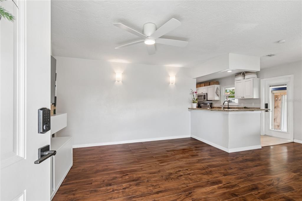 An open-concept living area features wood-look tile flooring, a ceiling fan, and a kitchen pass-through — 3912 W LEILA AVENUE, TAMPA, FL