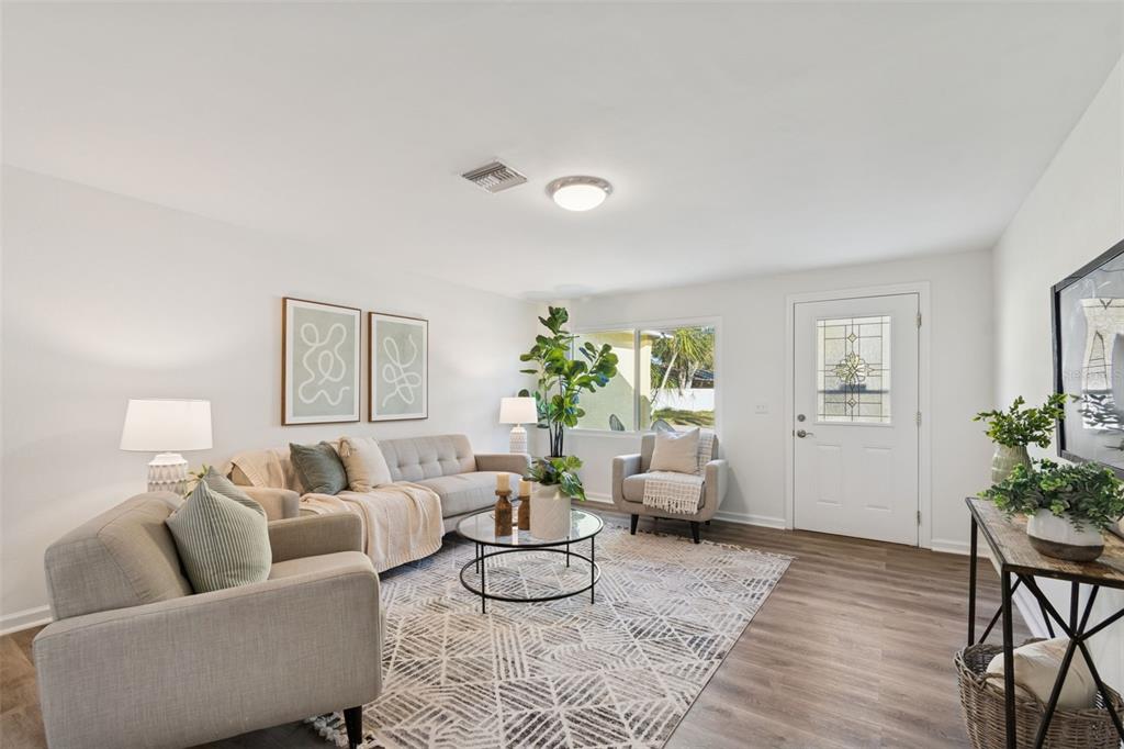 A living room with wood-look flooring, a beige sofa, and an open kitchen beyond — 2195 GLEN DRIVE, SAFETY HARBOR, FL