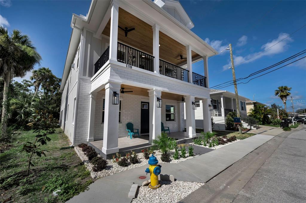 A two-story house with a white brick facade, a front porch, and a balcony — 158 E SPRUCE STREET, TARPON SPRINGS, FL